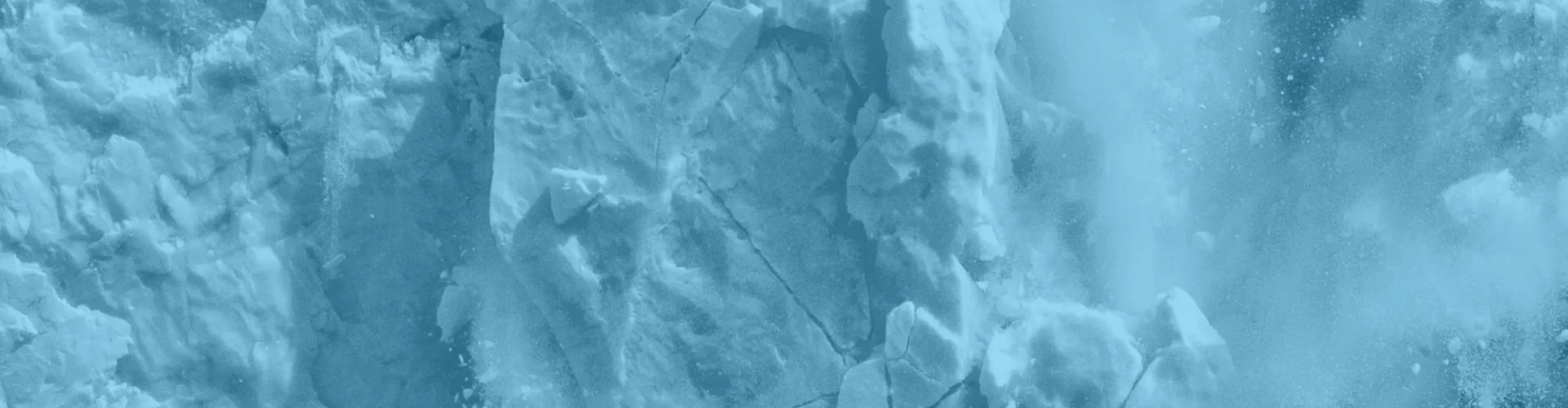 Tinted detail of a photo: Huge block of blue and white ice collapsing from a glacier front, shattering into fragments and throwing up a large white splash where it hits the dark water.